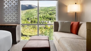 Habitación de hotel con un ventanal que ofrece vistas a un paisaje boscoso.