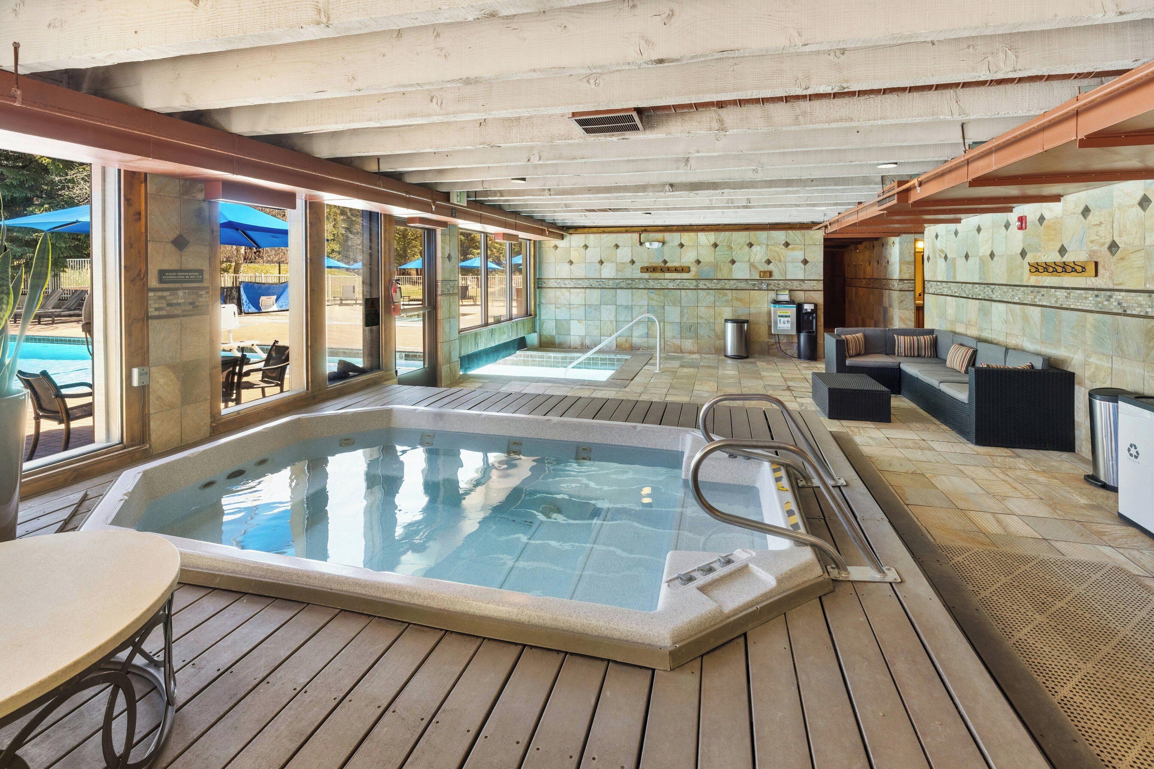 Un área de hidromasaje con piscina, terraza de madera y zona de estar con sofá y sillones.