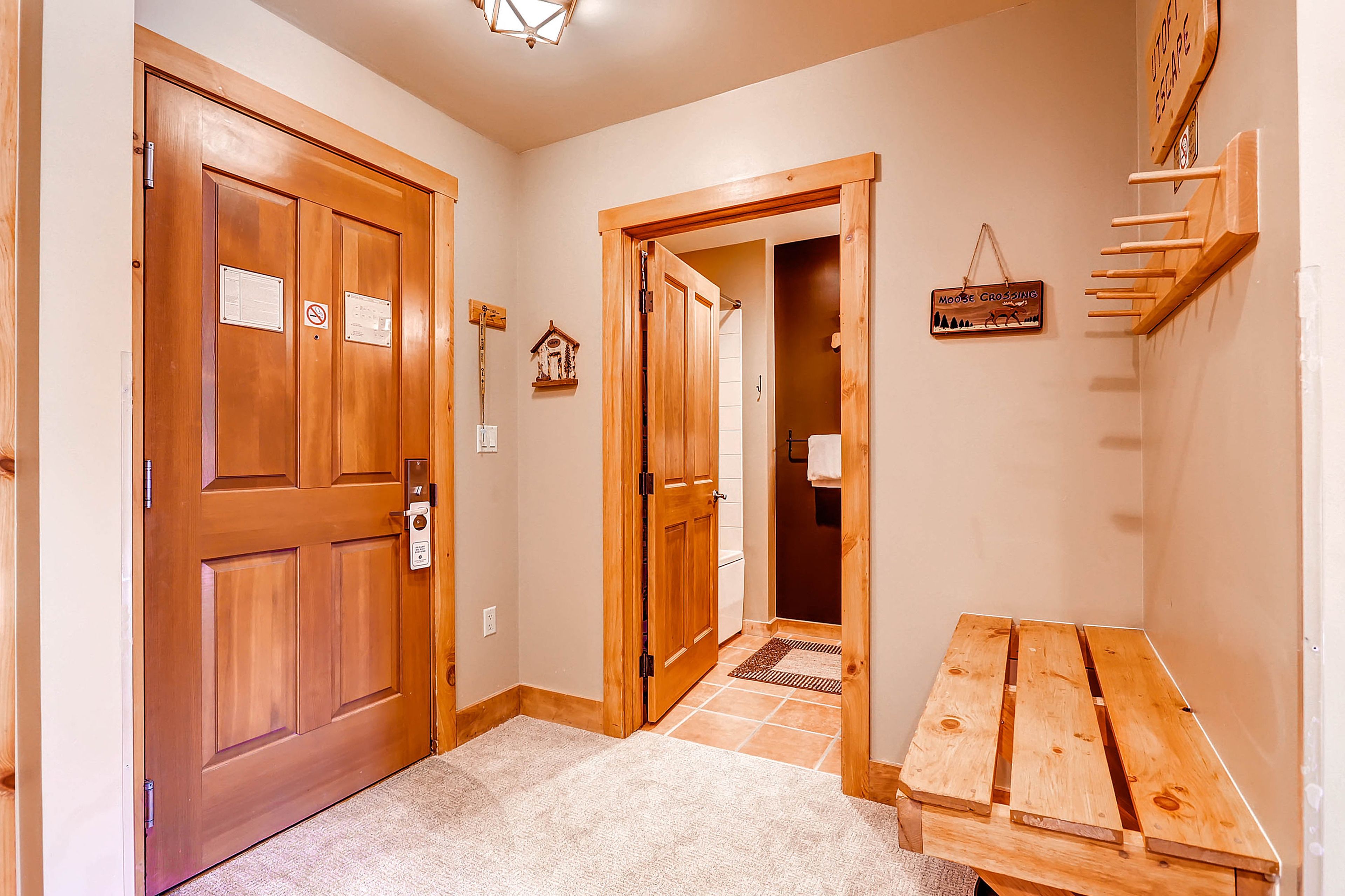 A hallway with wooden doors, a bench, and a small table.