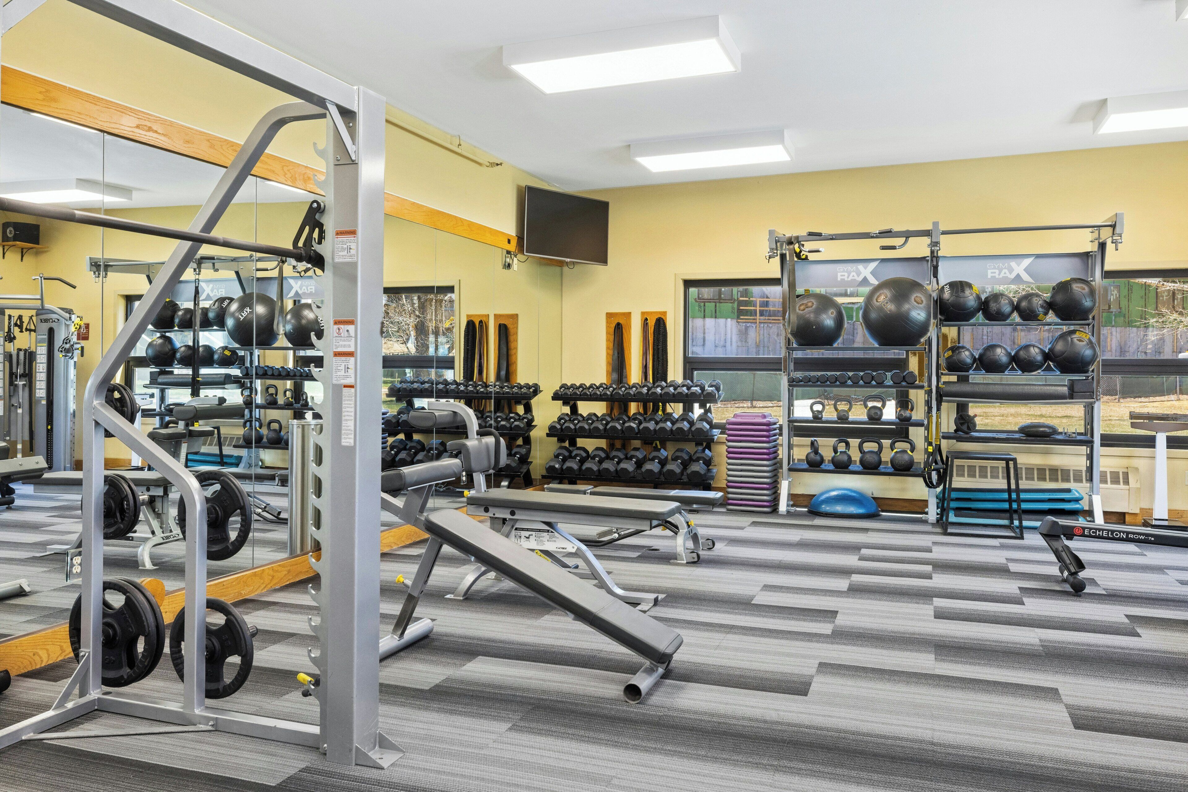 A gym with weightlifting equipment, exercise balls, and dumbbells.