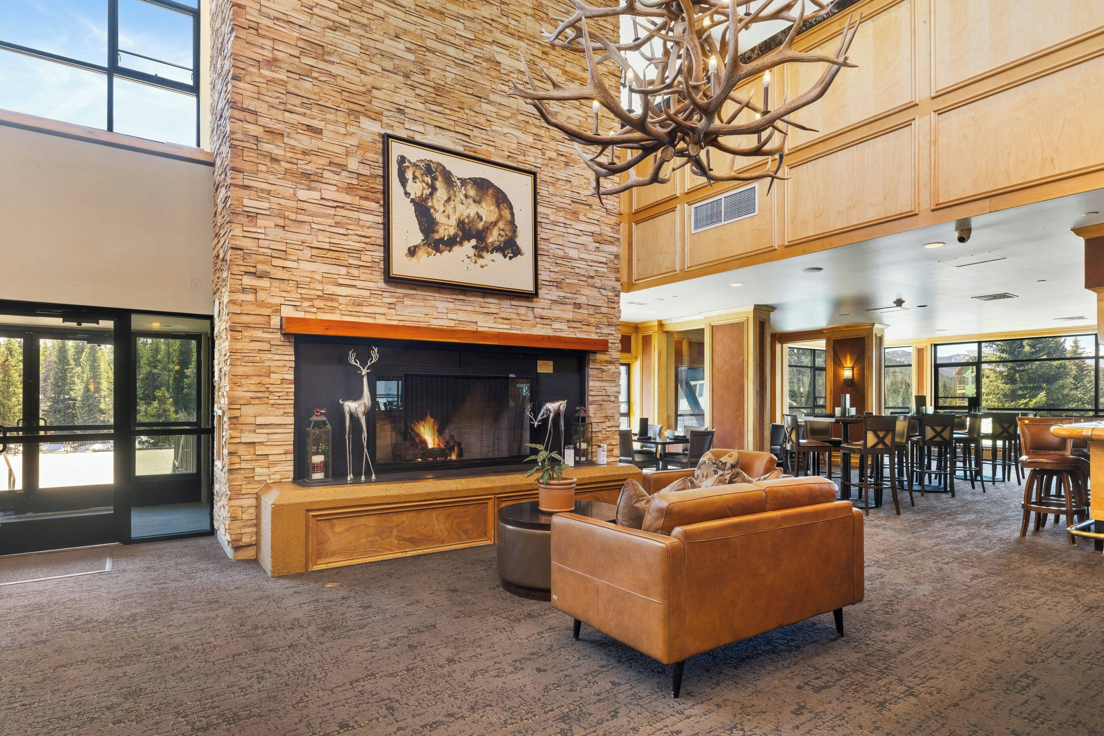 A spacious lobby with a stone fireplace, leather seating, and a high ceiling with a chandelier.