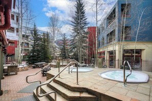 A public outdoor area with a hot tub, steps, and benches.