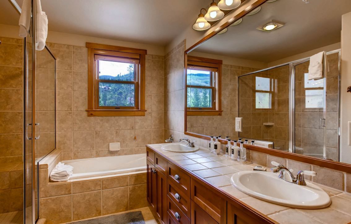 A modern bathroom with a double sink vanity, a large mirror, and a walk-in shower.