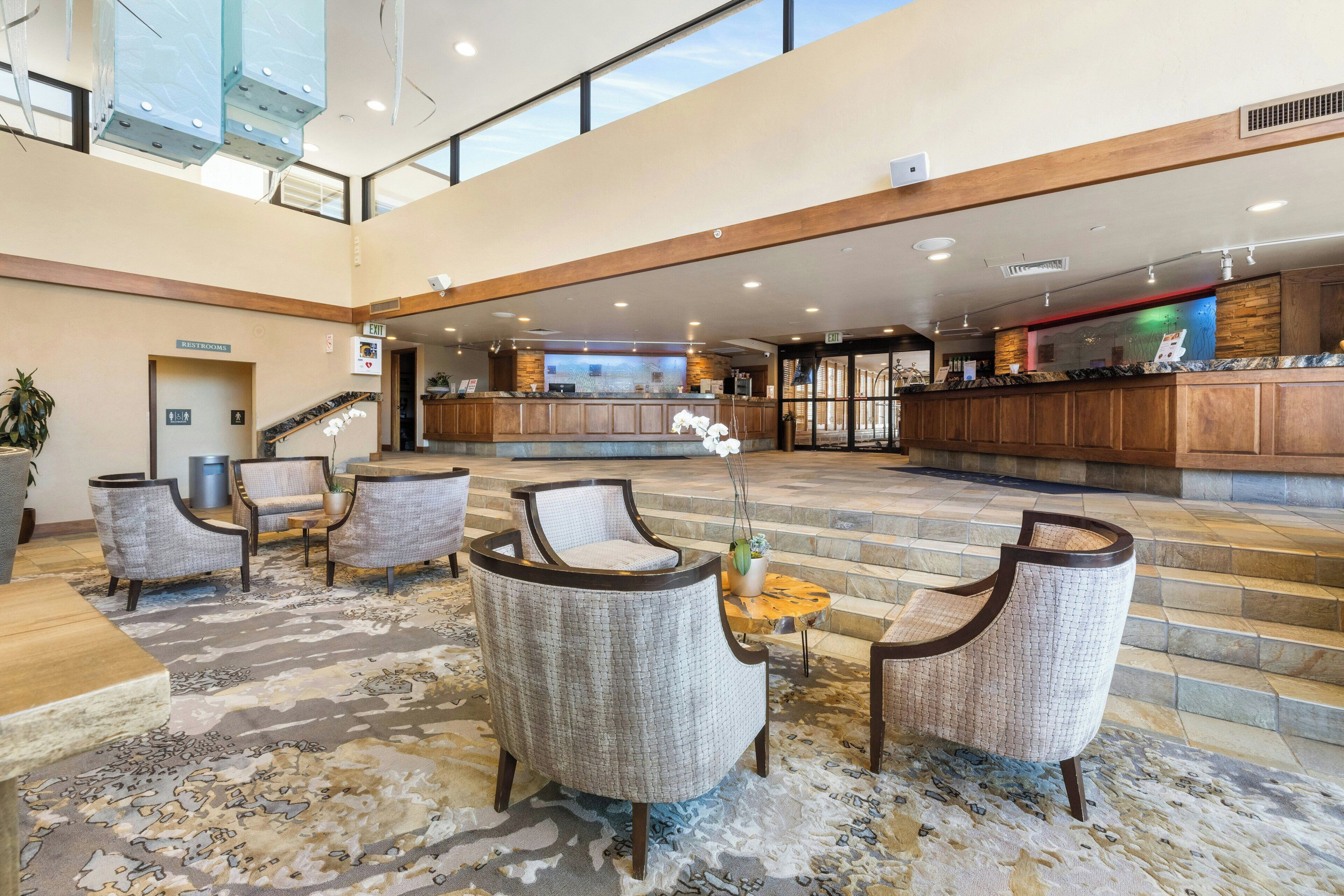 A spacious lobby with a reception desk, seating area, and a staircase leading to upper floors.
