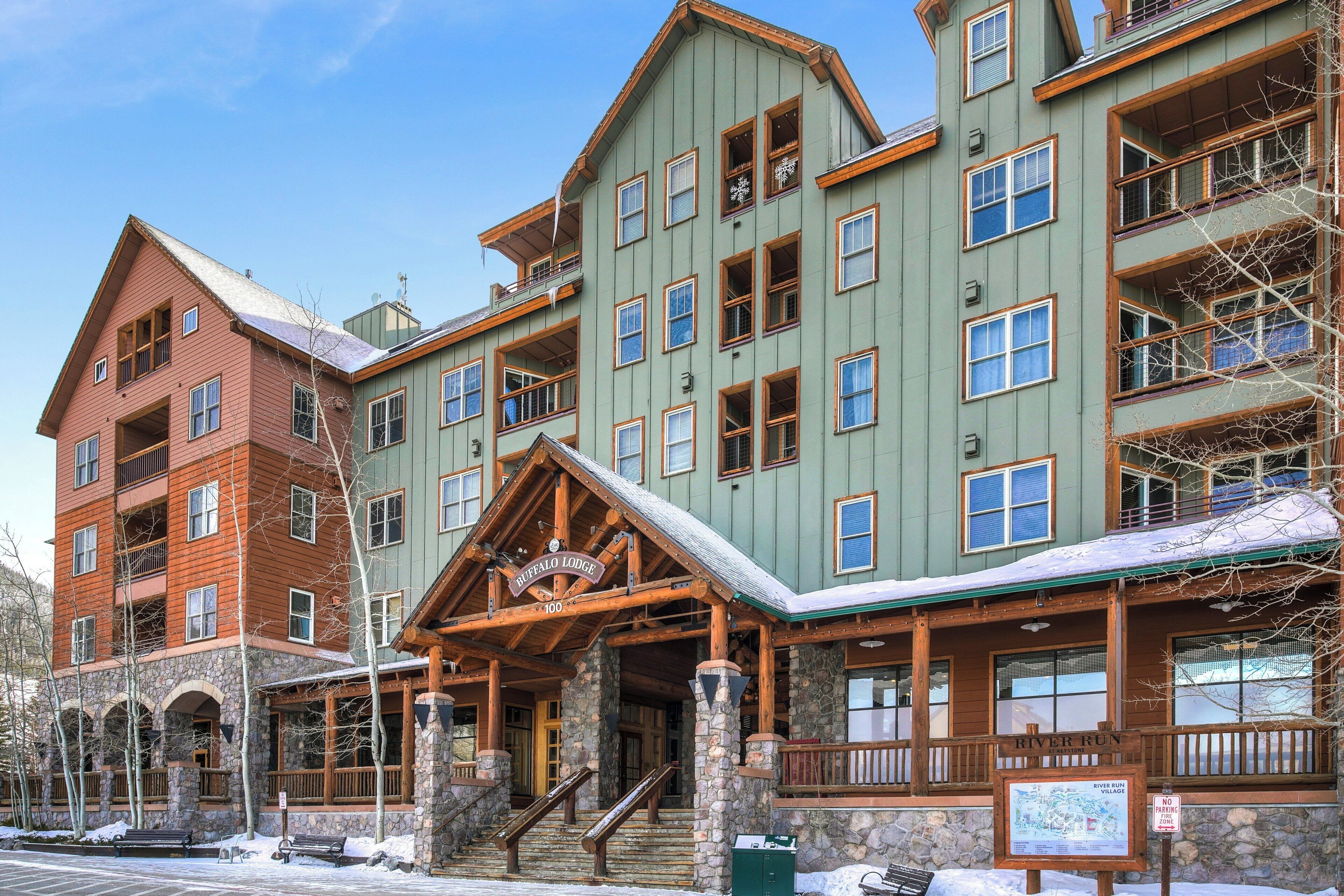 A multi-story lodge with a prominent entrance, stone pillars, and a sign indicating the name 'Buffalo Lodge.'