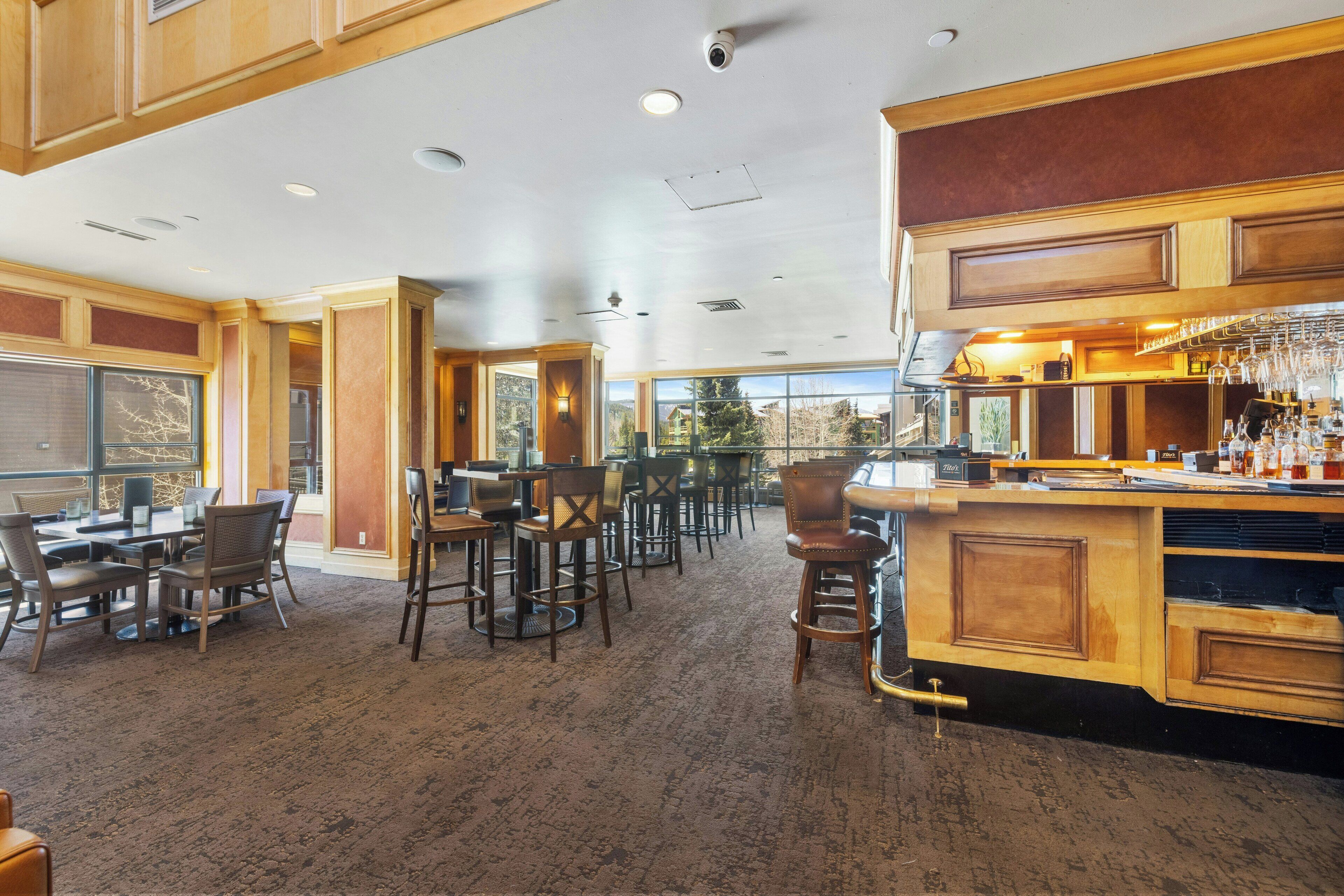 A spacious dining area with high ceilings, wooden paneling, and large windows offering a view of the outdoors.
