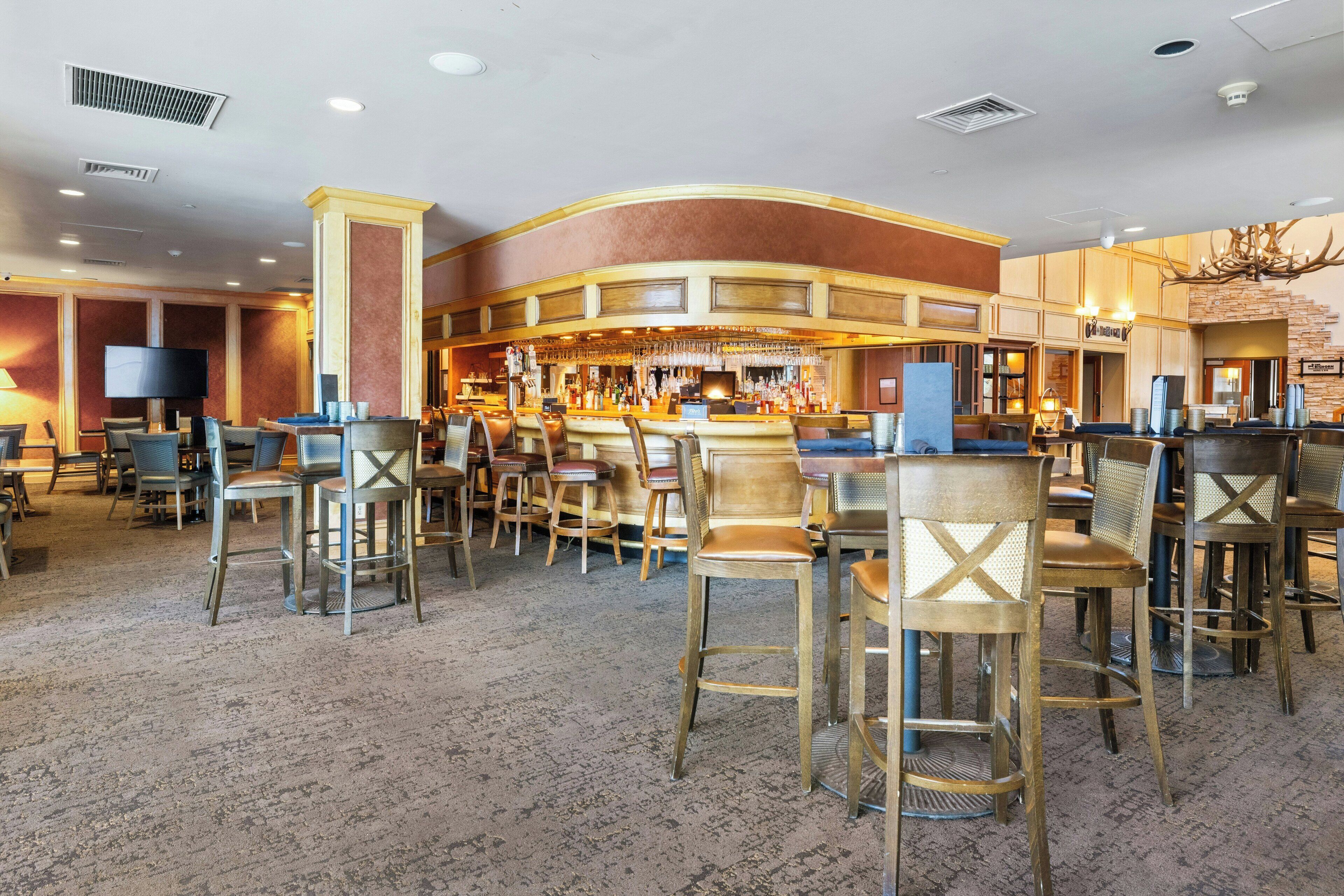 A bar area with multiple seating options, including bar stools and chairs, and a television screen.