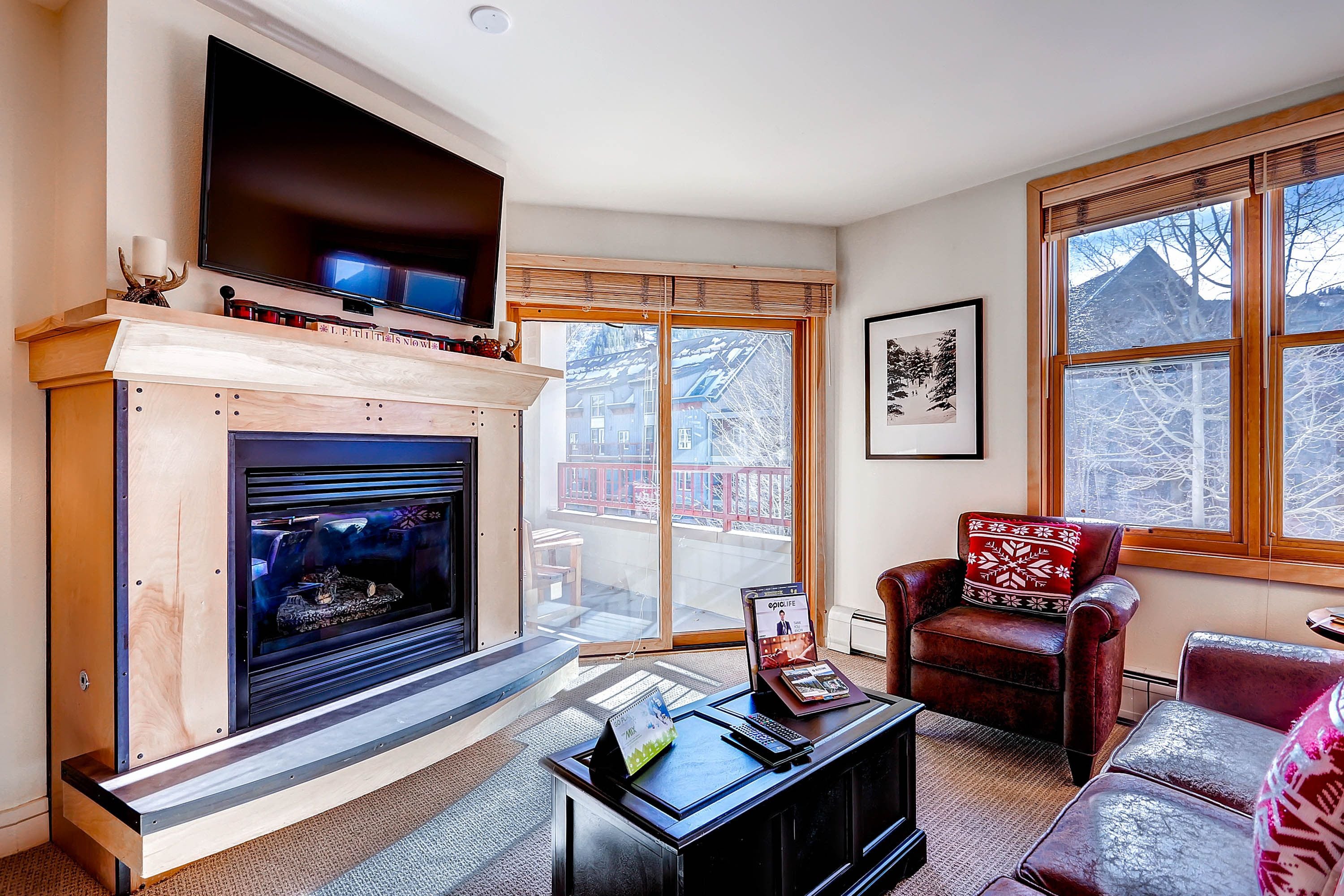 A living room with a fireplace, a television, and a large window with a view of buildings.