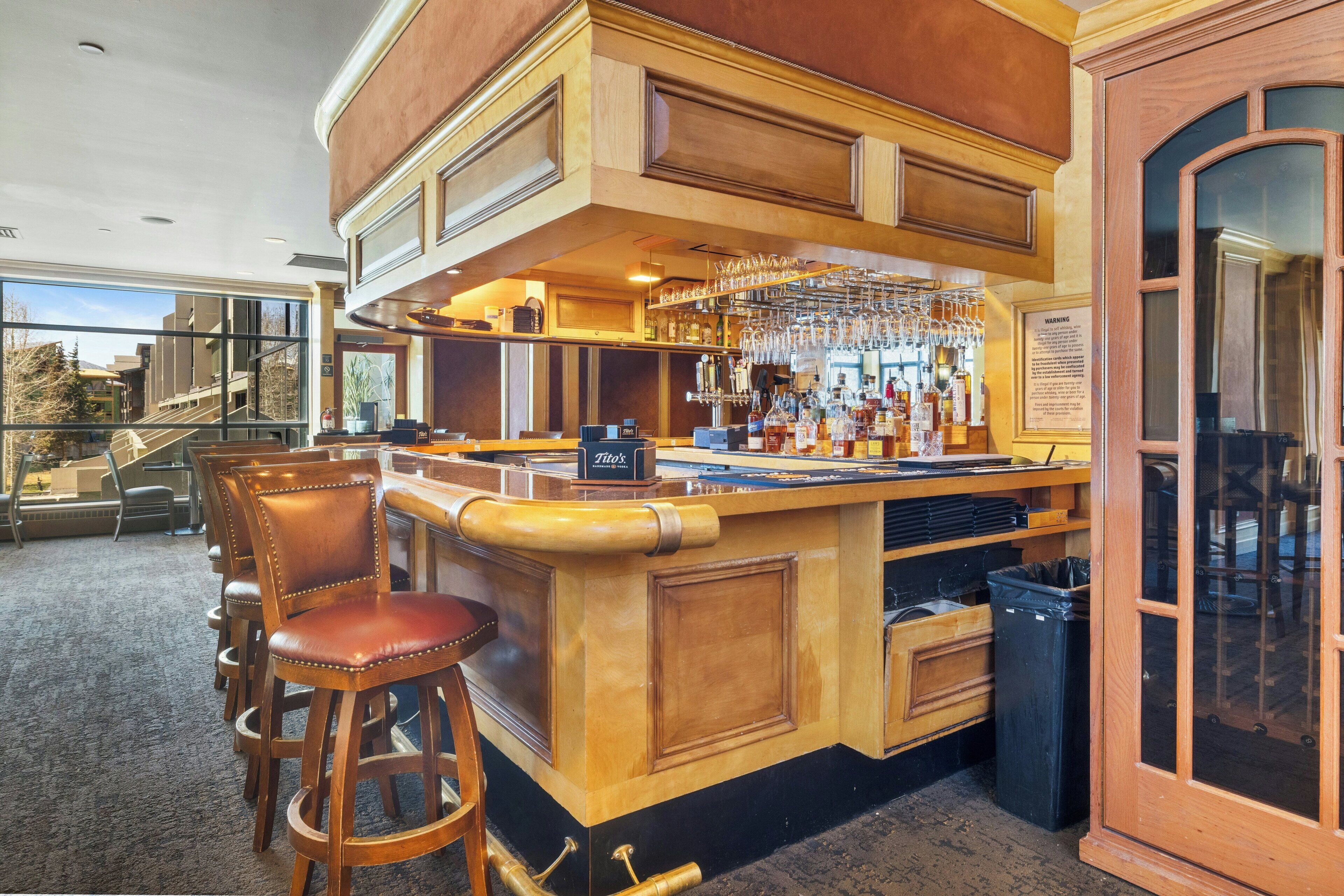 A bar area with wooden bar stools, a bar counter, and a glass display case.