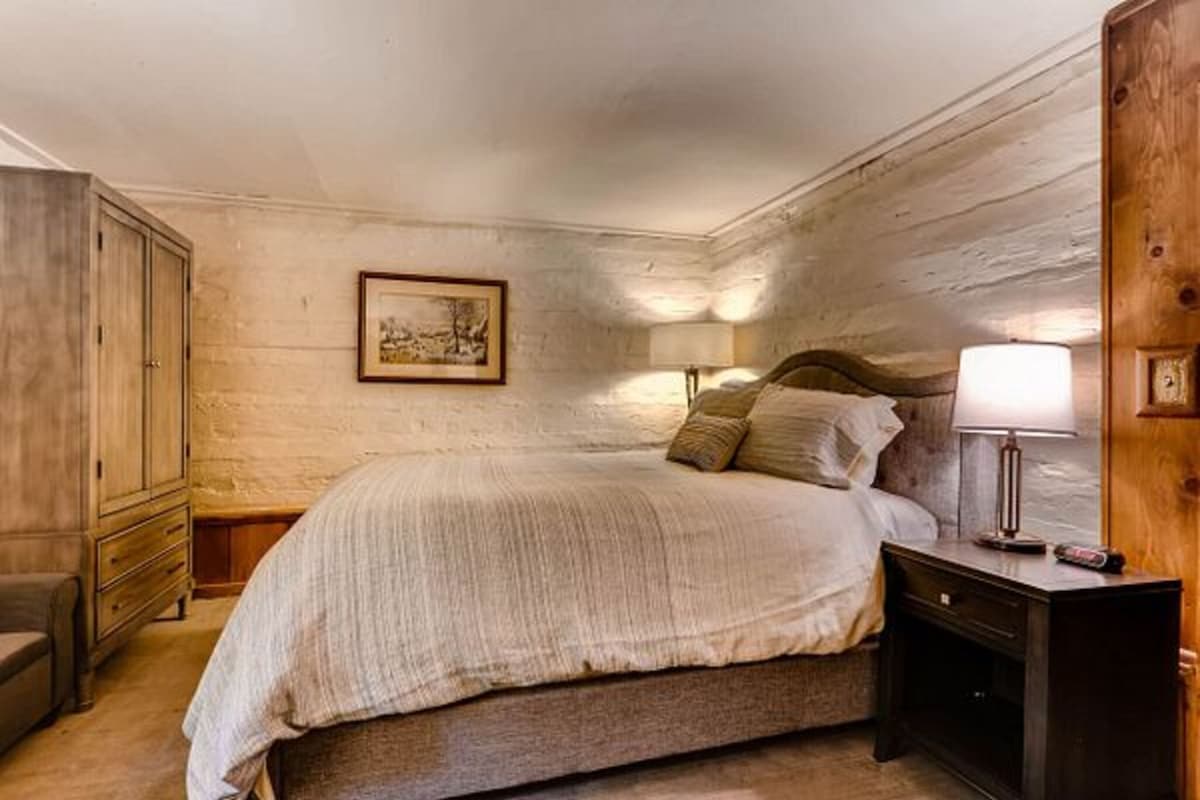 A bedroom with a bed, wooden wardrobe, nightstands, and a framed picture on the wall.