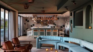 A modern bar area with a curved seating arrangement, a bar counter, and a variety of bottles and glasses. - Kimpton Banneker Hotel by IHG (Washington)