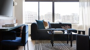 A modern living room with a sofa, chairs, a coffee table, and a TV. - Kimpton Banneker Hotel by IHG (Washington)