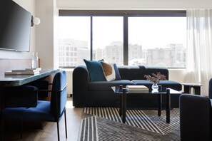 Un salon moderne avec un canapé, des fauteuils, une table basse et un téléviseur.