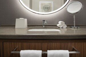 A bathroom with a sink, mirror, and towel rack.