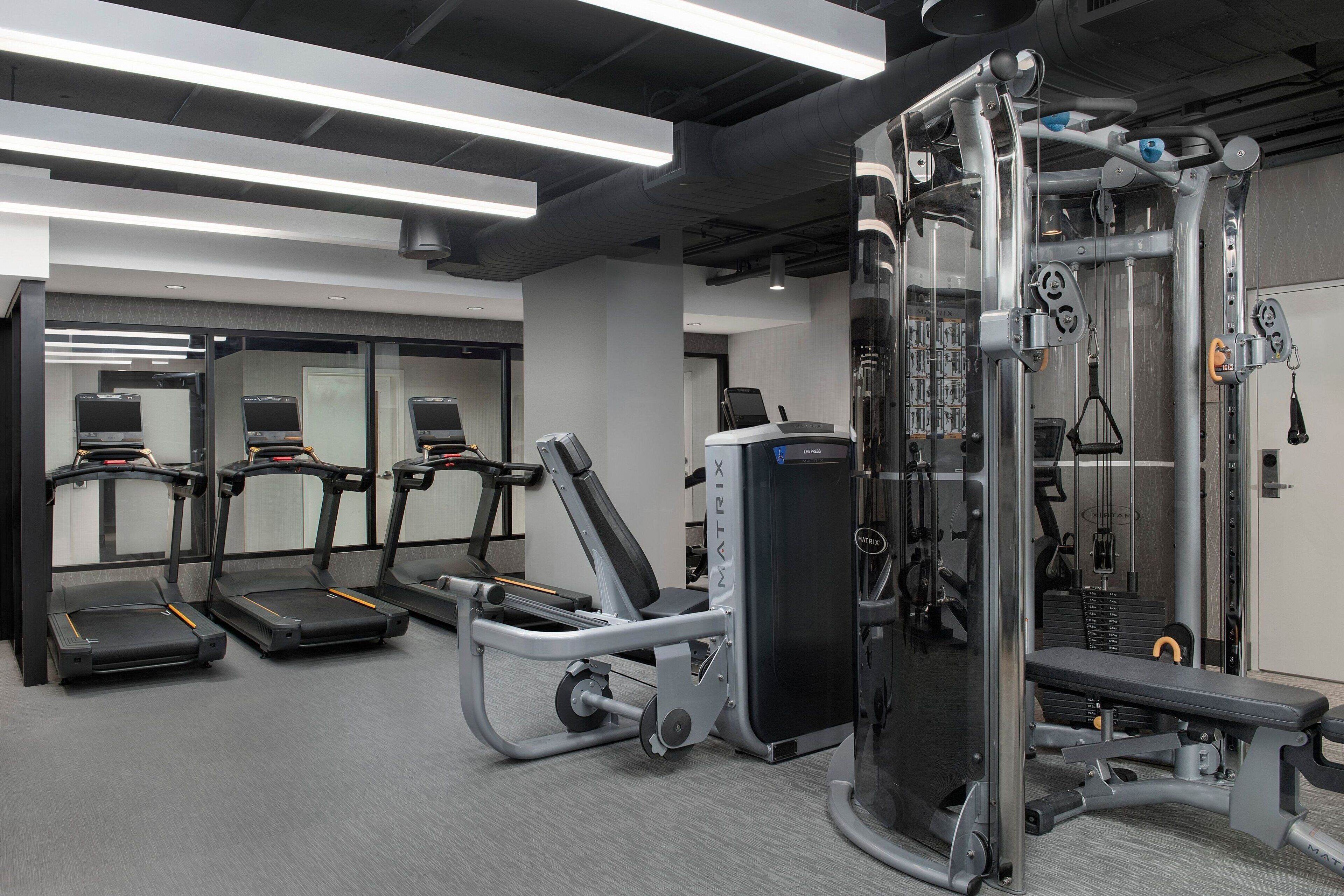 Academia moderna com esteiras, suporte para agachamento e máquinas de musculação.