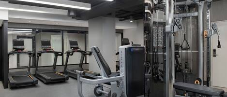 Academia moderna com esteiras, suporte para agachamento e máquinas de musculação.