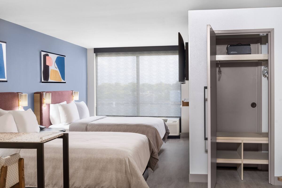 A hotel room with two beds, a desk, a TV, and a wardrobe.