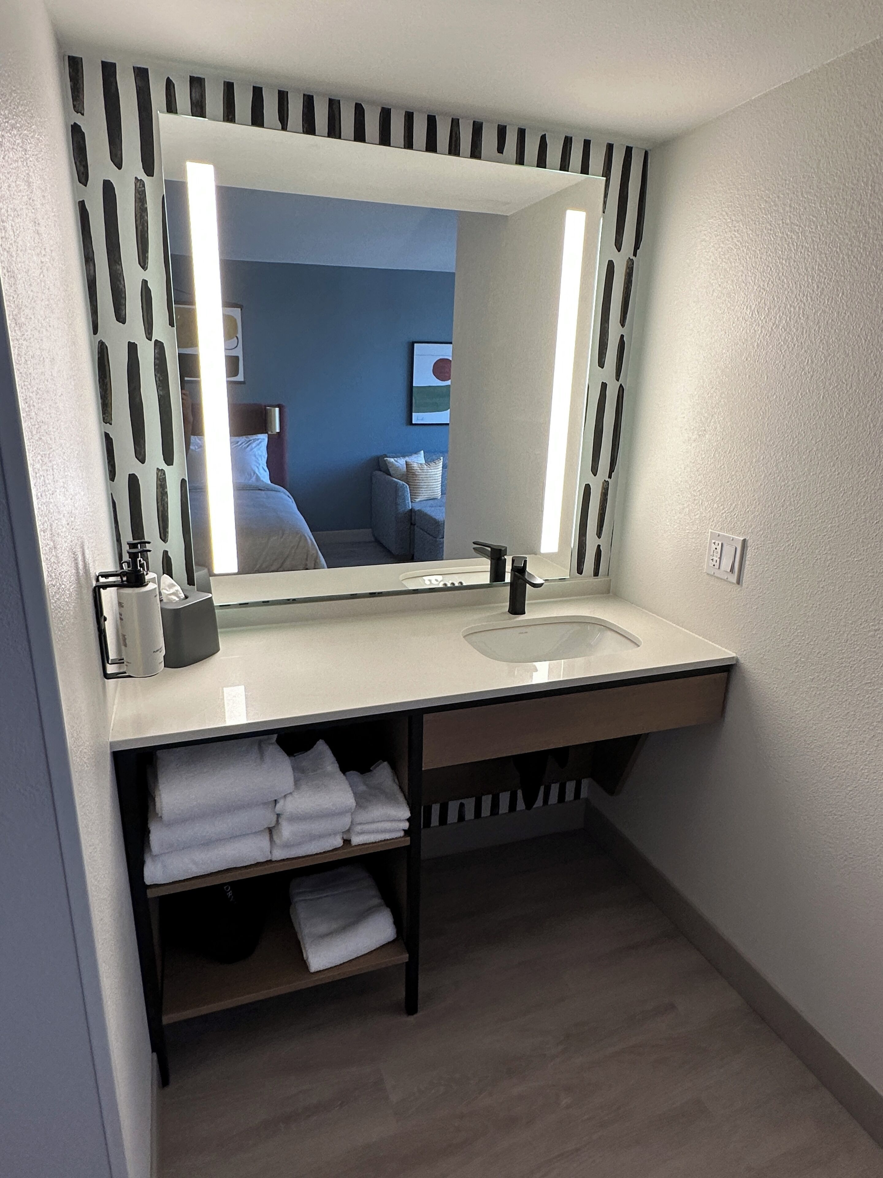 Un baño moderno con un espejo grande, un lavabo y un perchero para toallas.