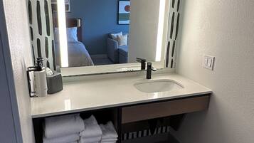 Un baño moderno con un espejo grande, un lavabo y un perchero para toallas.