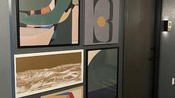 Un pasillo con suelo de madera, una puerta y cuatro obras de arte enmarcadas en la pared.