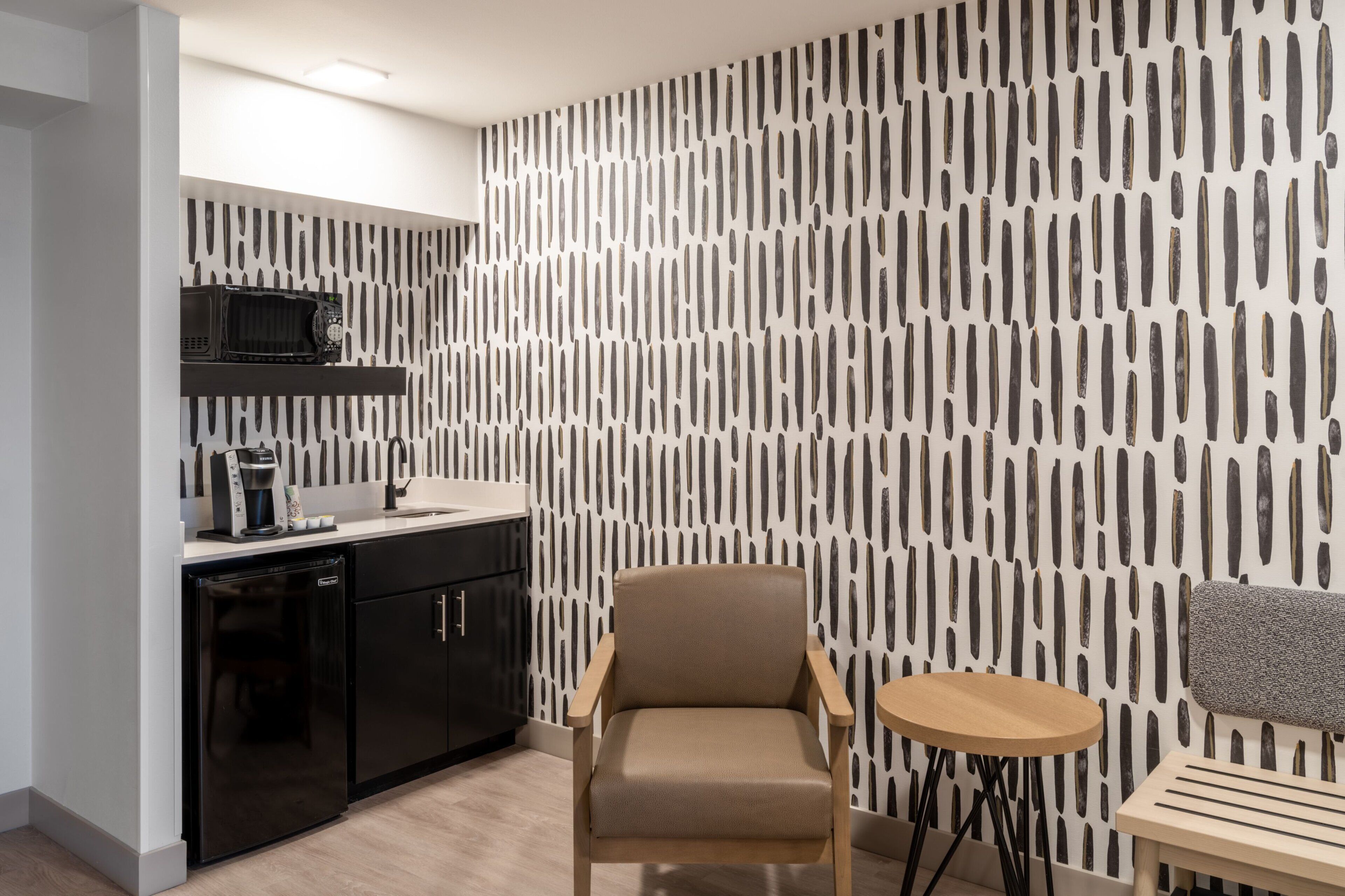 Une cuisine moderne équipée d’un four à micro-ondes, d’une machine à café et de meubles de couleur noire.