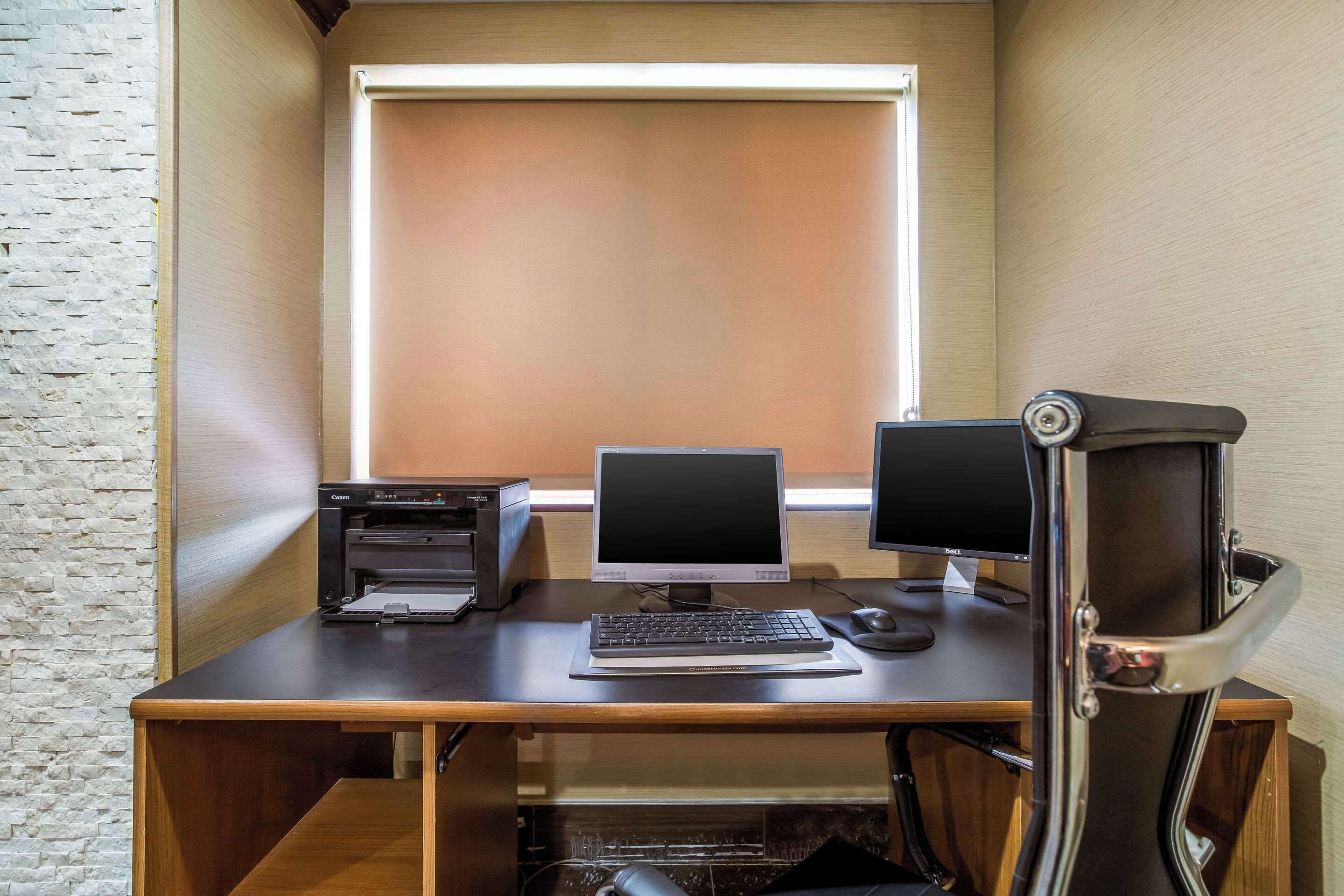 Un espacio de trabajo con escritorio, dos monitores, una impresora y un teclado.