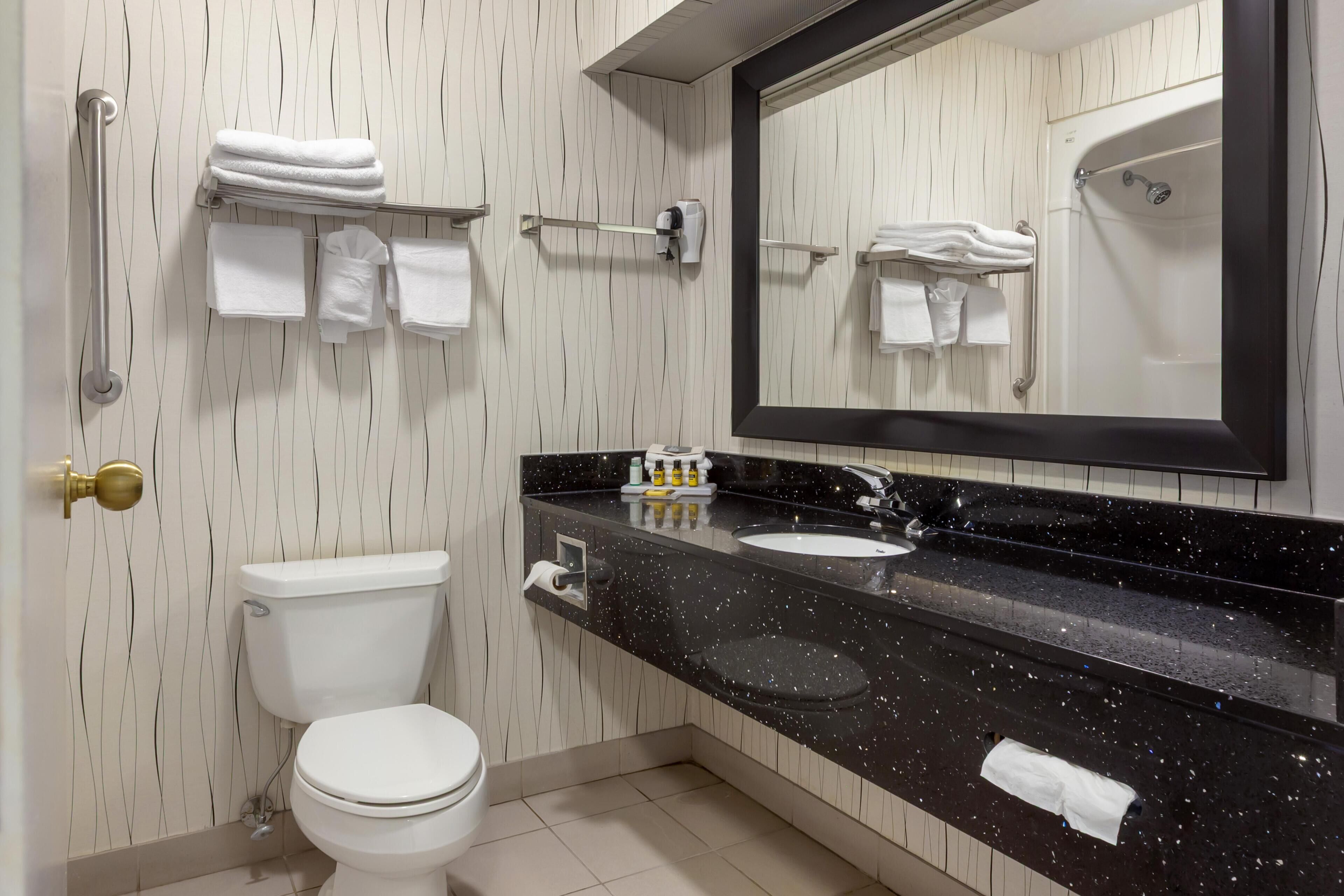 Een moderne badkamer met toilet, wastafel en spiegel.
