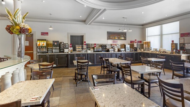 A restaurant with marble tables and chairs, a kitchen area, and a large window.
