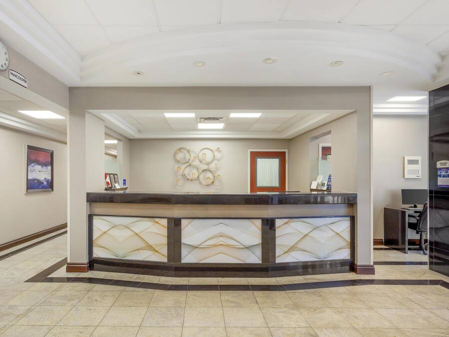 A reception desk with a clock, framed artwork, and a decorative wall piece.