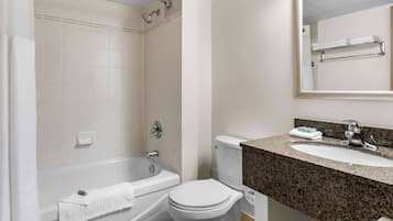 A bathroom with a bathtub, toilet, sink, and a mirror.