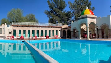 Relax by the rectangular pool surrounded by a low wall, adjacent to a building with arches and a dome.