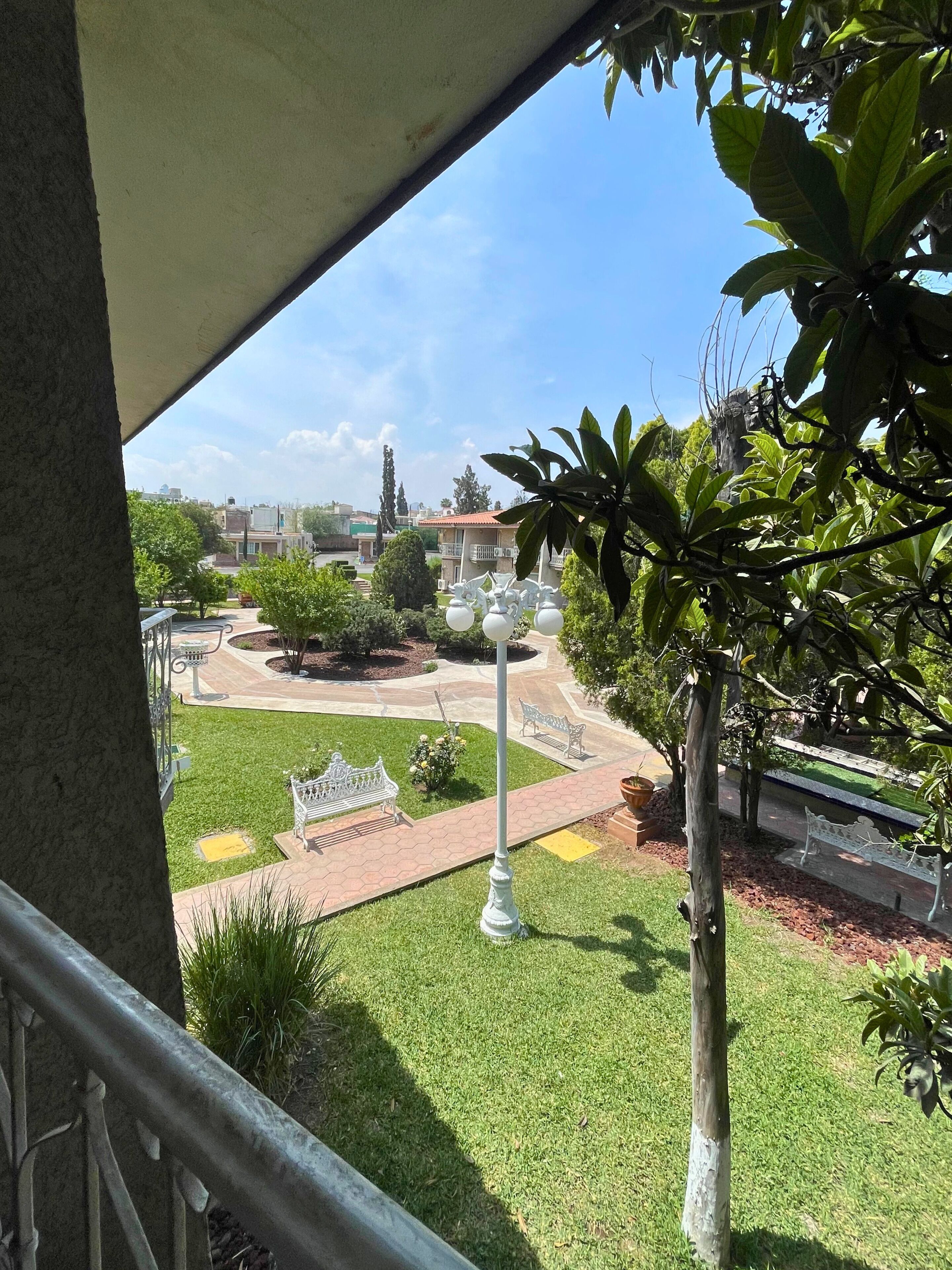 Vista de un patio bien cuidado con una fuente central, rodeado de bancos y follaje.