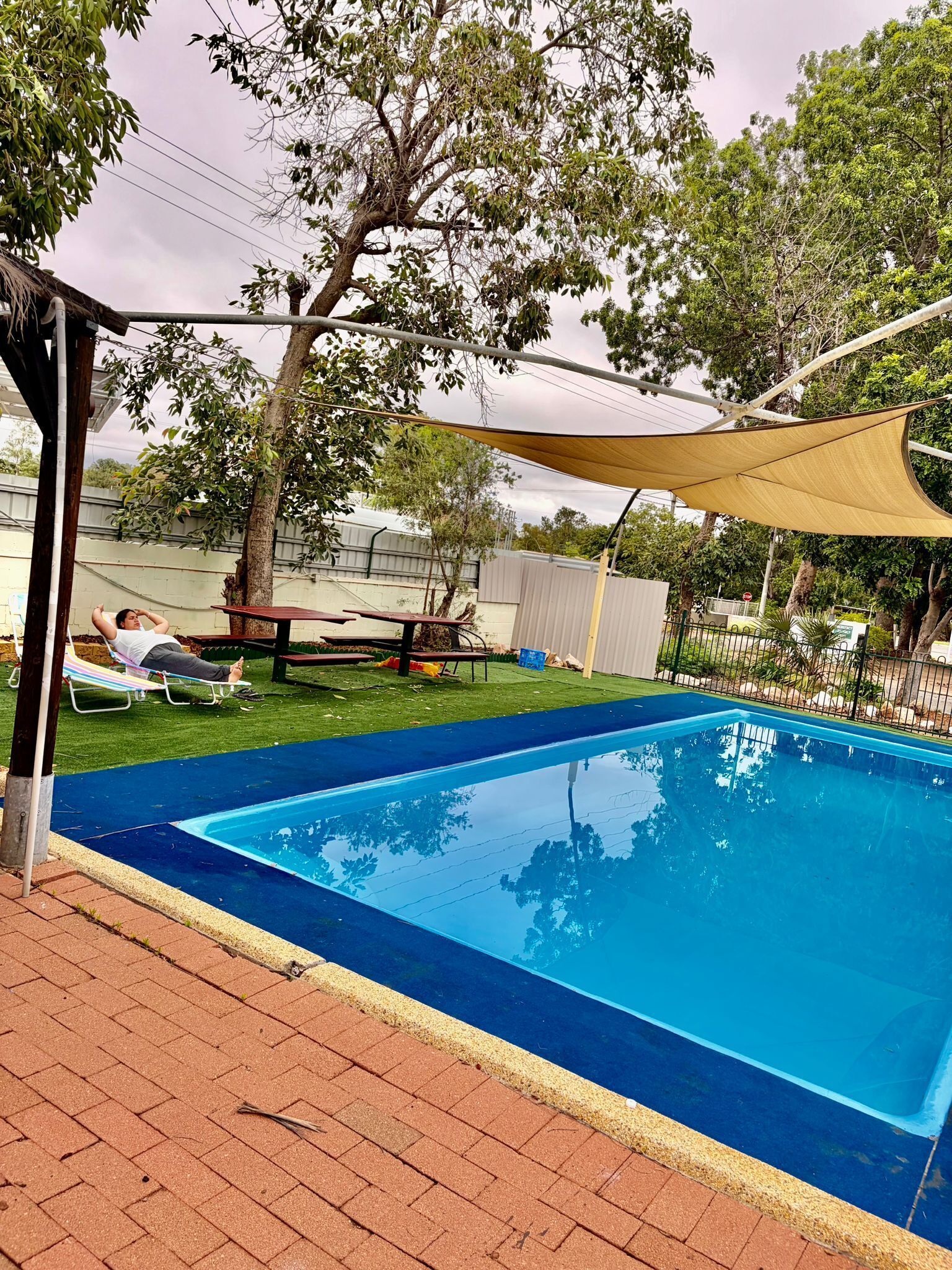 Una piscina con superficie de agua azul cristalina, rodeada por un patio de ladrillo.