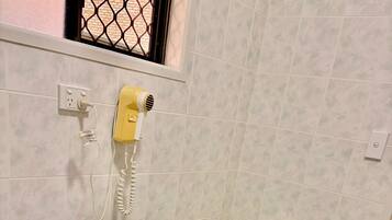 Un baño con un lavamanos blanco, un inodoro y un secador de pelo montado en la pared.