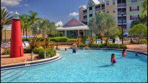A swimming pool with a red lighthouse, palm trees, and a building with balconies. - Holiday Inn Express & Suites S Lake Buena Vista by IHG (Kissimmee)