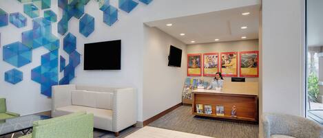 A reception area with a counter, seating, and a wall with geometric glass panels.