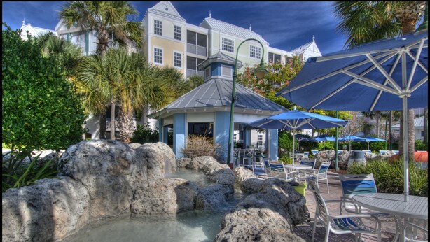 A resort pool area with a small gazebo, lounge chairs, and umbrellas. - Holiday Inn Express & Suites S Lake Buena Vista by IHG (Kissimmee)
