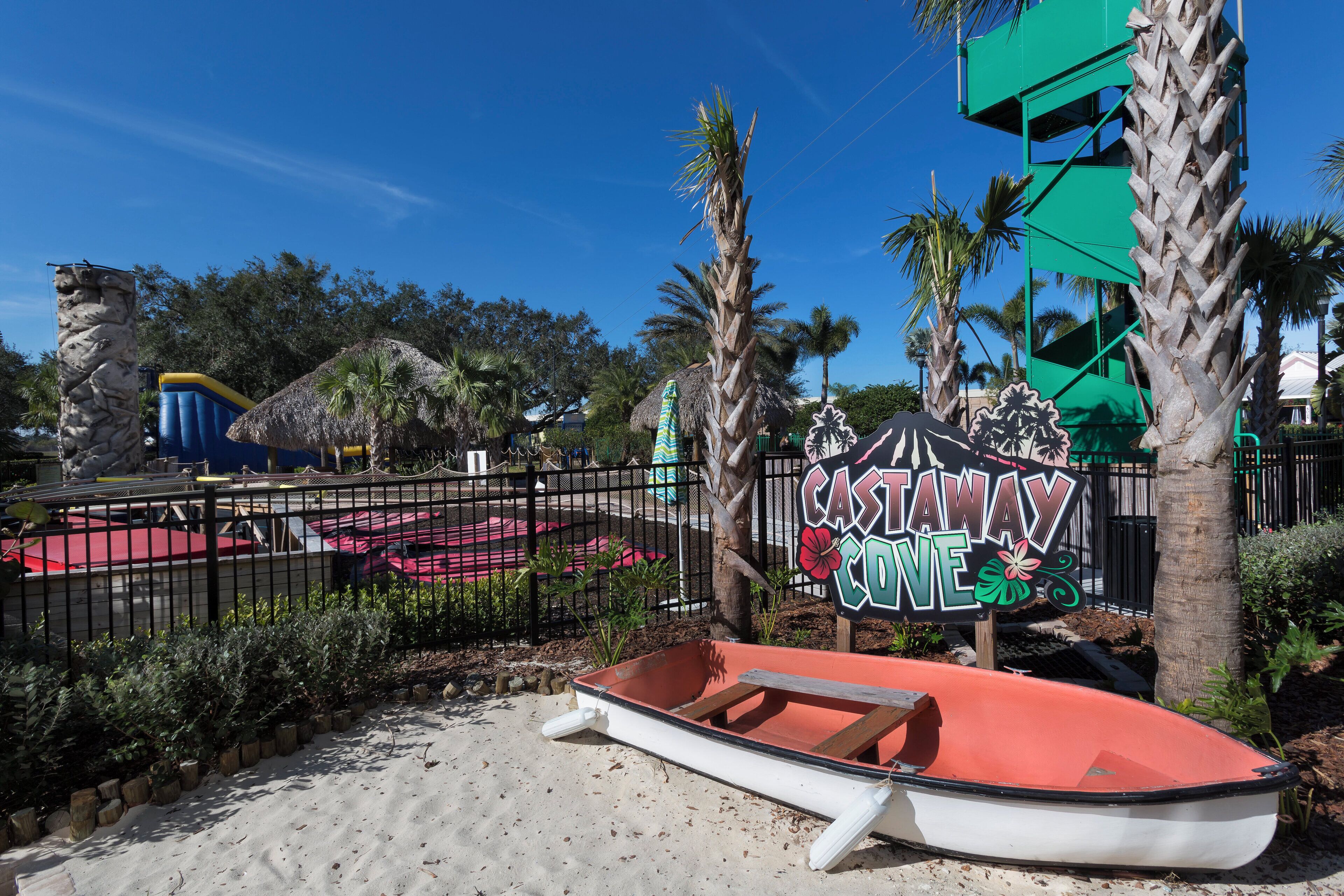 Un espace aménagé sur le thème de la plage, avec une pancarte indiquant « CASTAWAY COVE », un bateau et des palmiers.