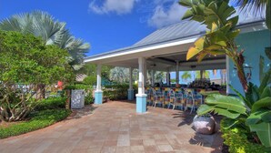 A covered outdoor seating area with a bar, surrounded by tropical plants and a clear blue sky. - Holiday Inn Express & Suites S Lake Buena Vista by IHG (Kissimmee)