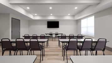 A conference room with a long table, multiple chairs, a flat-screen TV, and large windows.