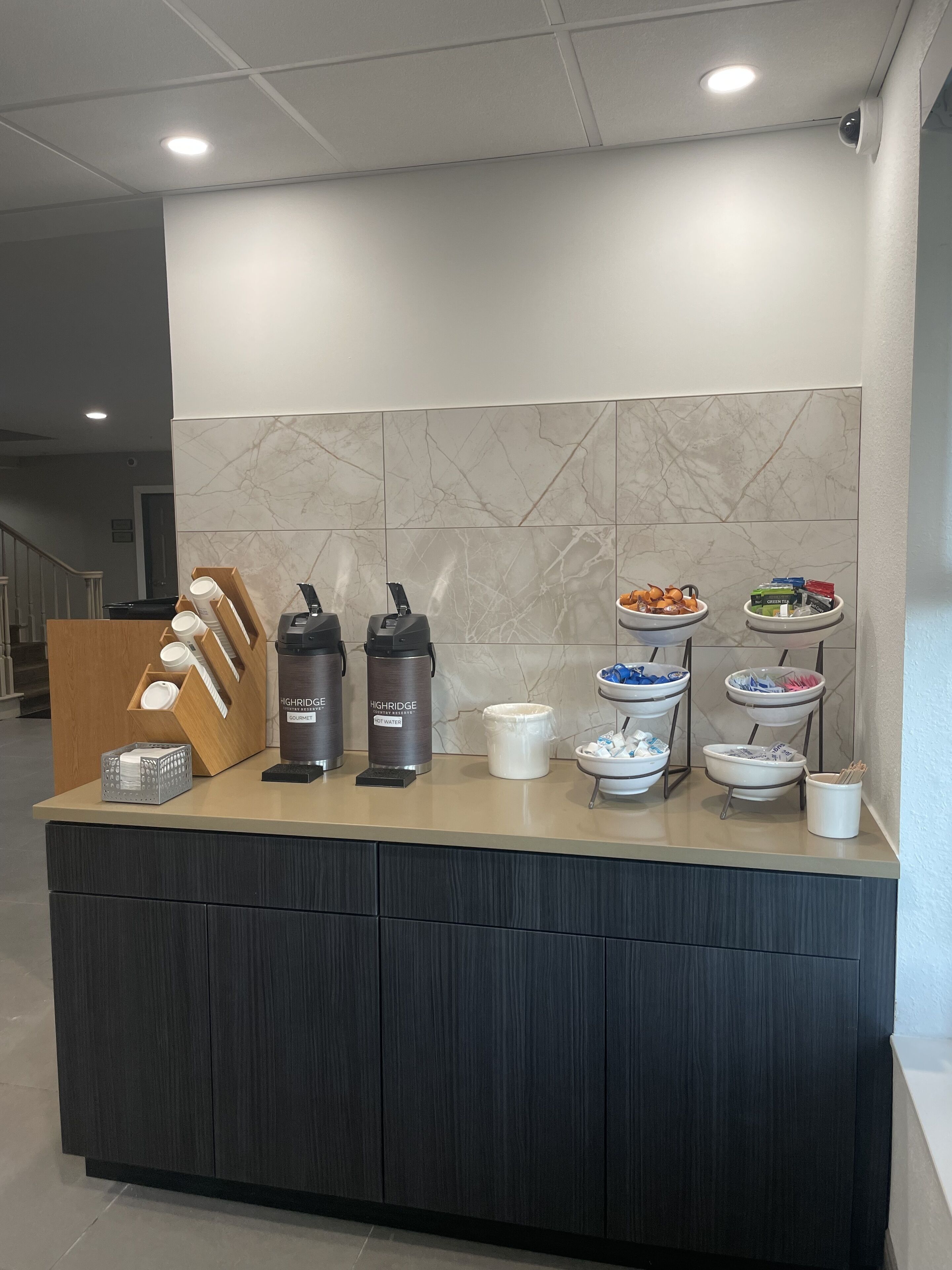 A self-service breakfast bar with coffee makers, hot water dispensers, and a variety of food items.