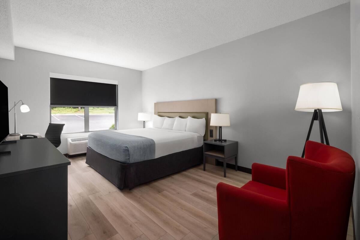 Une chambre d’hôtel moderne avec un grand lit, un bureau, une chaise et une vue sur l’extérieur.