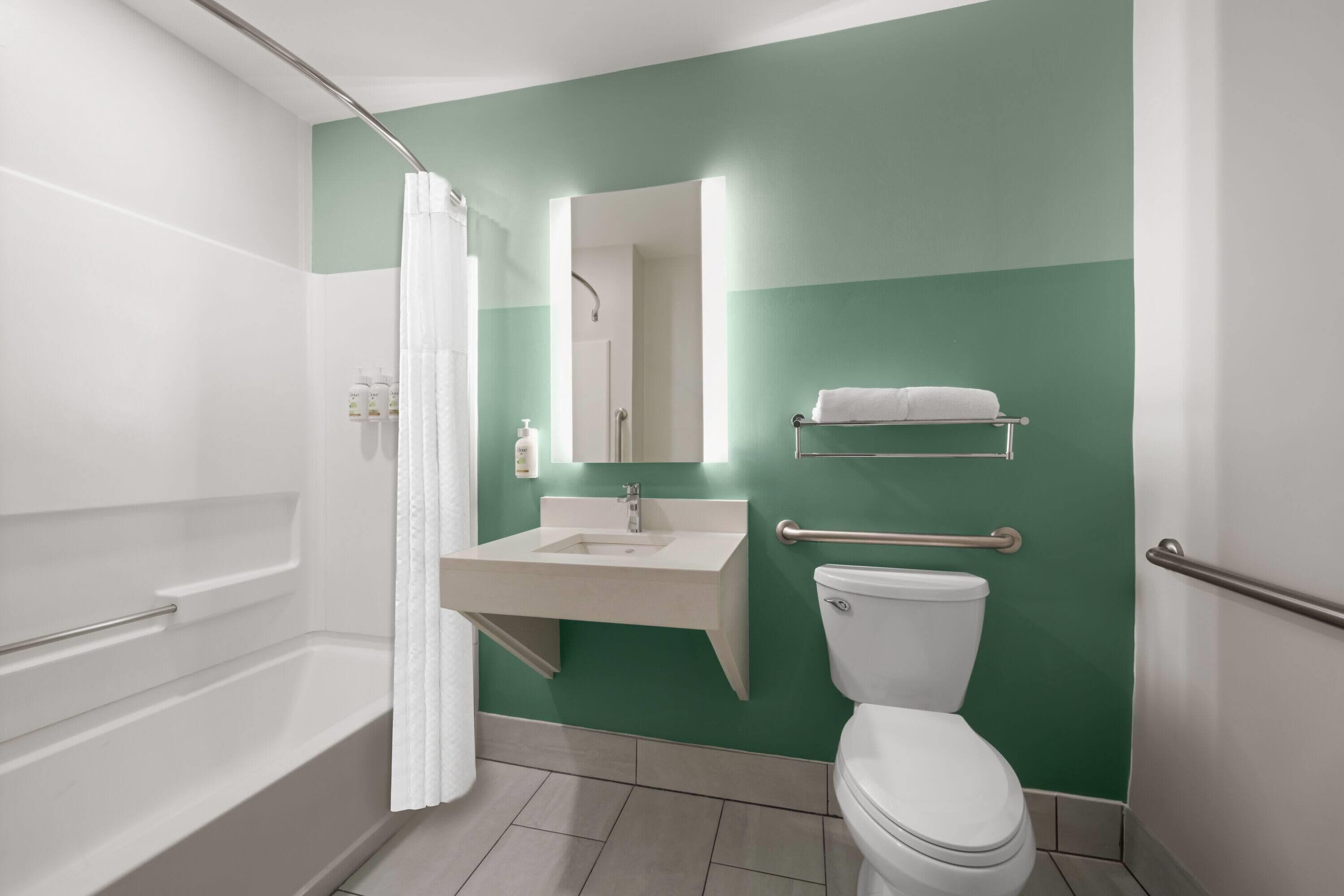 A bathroom with a bathtub, sink, toilet, and a mirror.