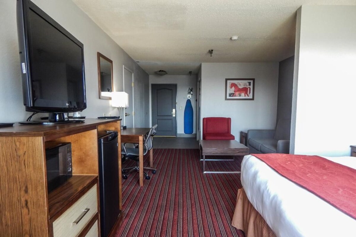 A hotel room with a bed, a desk with a computer, a television, and a chair.