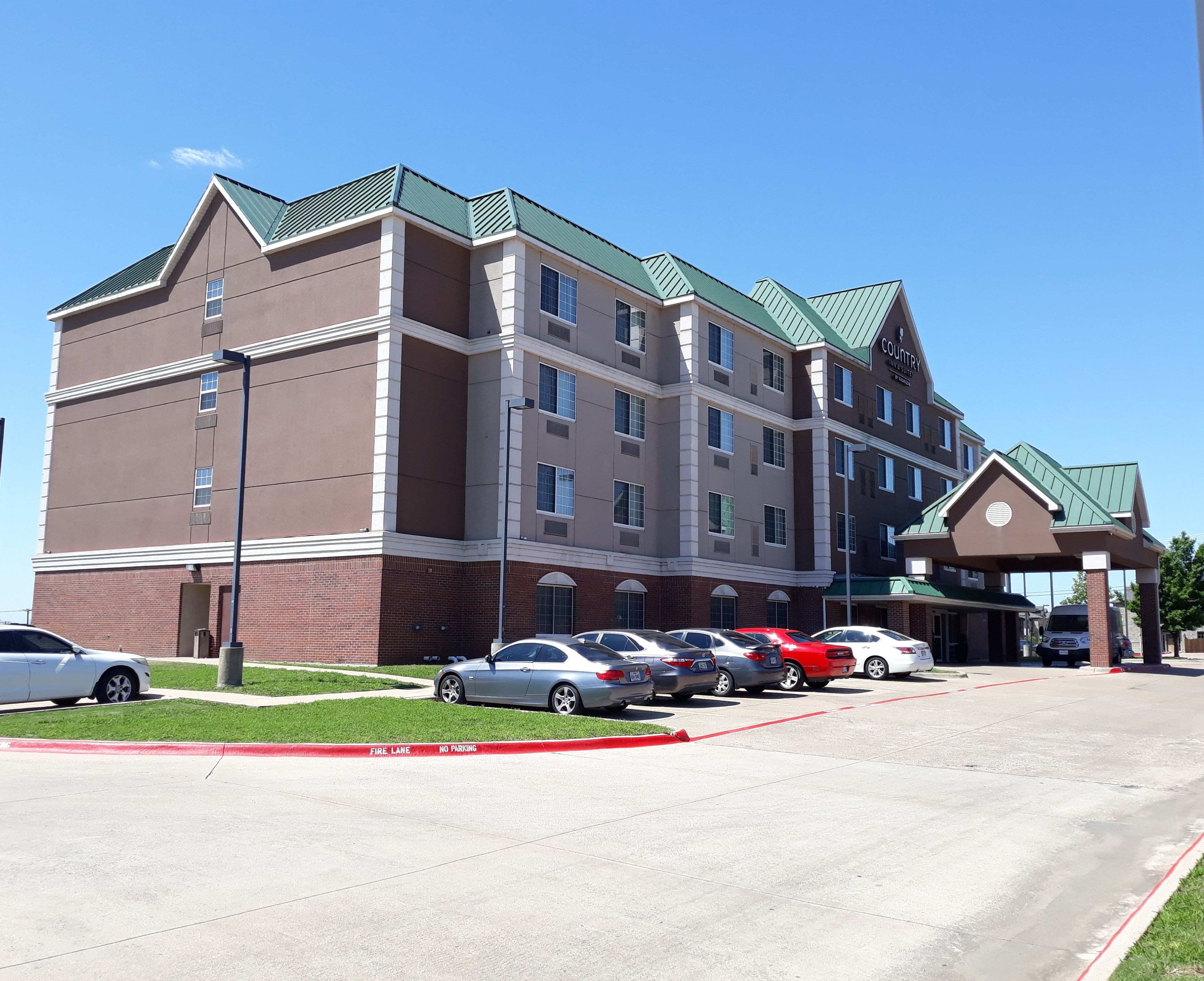 A multi-story hotel with a green roof and a fire lane marked by red curbs.