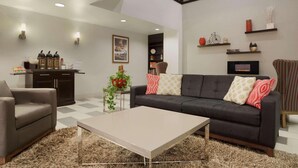 A modern living room with a sofa, armchair, coffee table, and decorative items. - Country Inn & Suites by Radisson, DFW Airport South, TX (Irving)