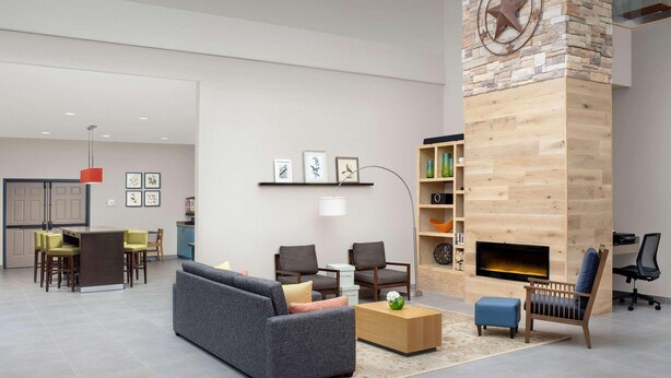 A modern living room with a fireplace, a sofa, chairs, and a dining area. - Country Inn & Suites by Radisson, Houston Intercontinental Airport East, TX (Humble)