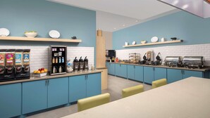 A modern kitchen with blue cabinets, a white brick backsplash, and various appliances. - Country Inn & Suites by Radisson, Houston Intercontinental Airport East, TX (Humble)