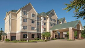 A large, multi-story hotel with a prominent entrance and a covered parking area. - Country Inn & Suites by Radisson, Houston Intercontinental Airport East, TX (Humble)