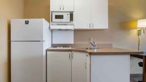 A compact kitchen with a refrigerator, microwave, sink, and cabinets. - Extended Stay America Suites Detroit Canton (Canton)